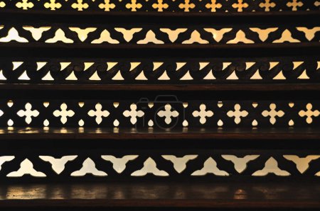 Photo for Decorative wooden stairs with lace-like openwork pattern, warm light shining through - Royalty Free Image