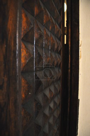una vista detallada de una parte de una puerta de madera con intrincados patrones geométricos, haciendo hincapié en la textura y la artesanía
