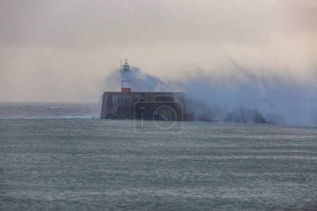 Téléchargez les photos : A view out to sea at Newhaven in Sussex, with waves crashing around the lighthouse - en image libre de droit