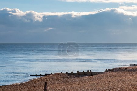 La playa de guijarros en Eastbourne en Sussex, con un océano tranquilo más allá