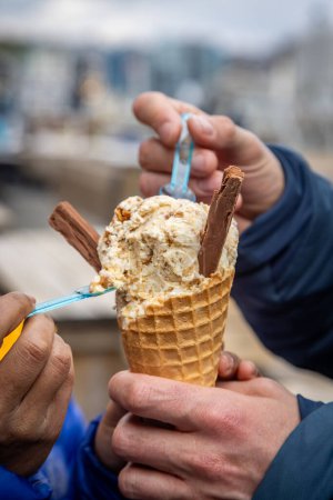 Un primer plano de dos personas compartiendo un cono de helado, con una profundidad de campo poco profunda