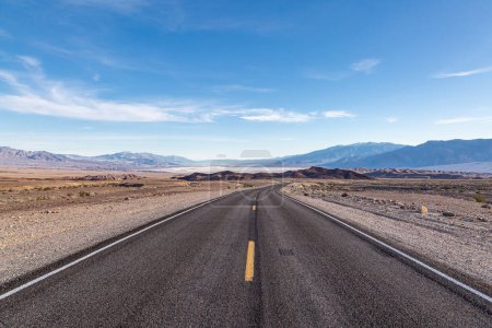 Looking along a highway leading to Death Valley in California, with a blue sky overhead