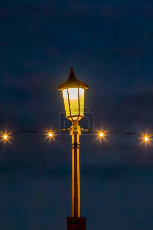 A street lamp and string lights against a night sky, on the promenade in Eastbourne