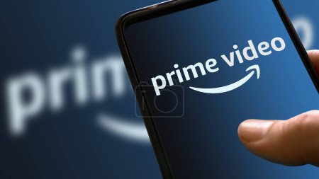 Photo for Prime video blue logo on mobile phone display with ramp color in the background. streaming movies and TV series platform icon on the smartphone screen holding hand. Italy, Milan, 24-01-22 - Royalty Free Image