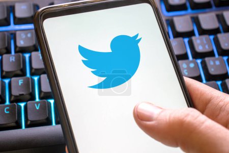 Foto de Teléfono móvil azul icono de twitter en pantalla en el teclado de color. Concepto de teléfono inteligente tweet símbolo red social - Imagen libre de derechos