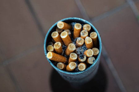Foto de Cenicero circular lleno de colillas de tabaco extinguido - Imagen libre de derechos