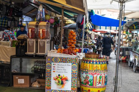 Foto de Palermo, Italia - 13 de mayo de 2023: Zumo de naranja en una tienda de frutas en Ballaro Market, mercado callejero de alimentos con gente en Palermo, Sicilia, Italia - Imagen libre de derechos