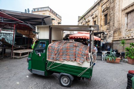 Foto de Palermo, Italia - 13 de mayo de 2023: Triciclo Piaggio estacionado en el mercado Ballaro, mercado callejero de alimentos con gente alrededor en Palermo, Sicilia, Italia - Imagen libre de derechos