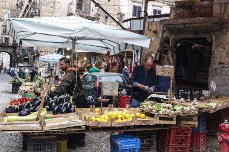 Foto de Palermo, Italia - 13 de mayo de 2023: Vendedores en una tienda de frutas y verduras, uno de ellos contando dinero, en el mercado Ballaro, mercado callejero de alimentos en Palermo, Sicilia, Italia - Imagen libre de derechos