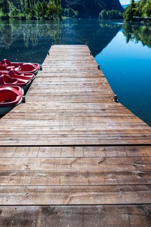 Foto de Muelle con pedalo y pasarela de madera en el Lago Torrassa para practicar deportes acuáticos de aventura en los Pirineos de Lleida, Cataluña, España - Imagen libre de derechos