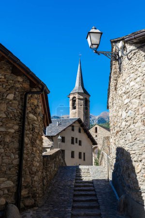 Narrow street and the bell tower of the church of Sant Vicenc of the rustic village of Esterri Aneu, Lleida, Catalonia, Spain