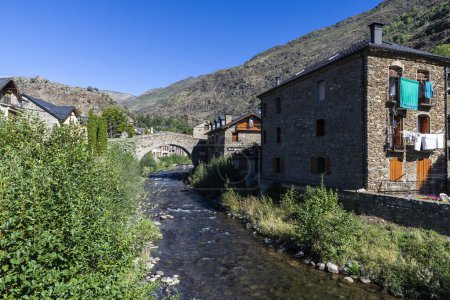 Typical houses and the Romanesque bridge over the Noguera Pallaresa river of the rustic village of Esterri Aneu, Lleida, Catalonia, Spain