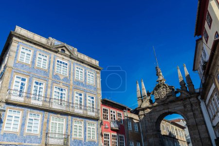 Foto de Arco triunfal de la Puerta Nueva o Arco da Porta Nova y casas decoradas con azulejos en el casco antiguo de Braga, Portugal - Imagen libre de derechos