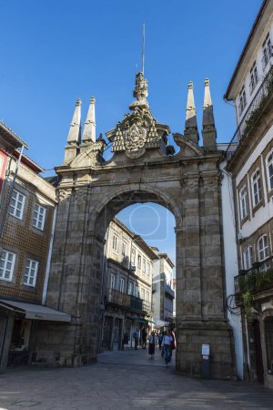 Foto de Braga, Portugal - 25 de noviembre de 2023: Arco triunfal de la Nueva Puerta o Arco da Porta Nova con gente alrededor en el casco antiguo de Braga, Portugal - Imagen libre de derechos