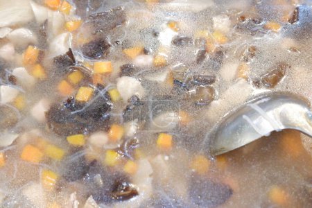 chicken soup in a pot with a spoon, closeup of photo