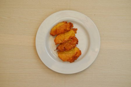 Croquetas de maíz en un plato blanco sobre una mesa de madera