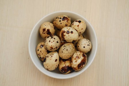 Quail eggs in a bowl on a wooden background. Selective focus.
