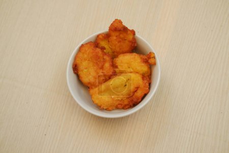 Corn croquettes in a bowl on a wooden table, top view