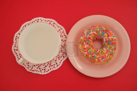 A pink plate with a donut and a cup of tea on top, creating a delightful and appetizing image.