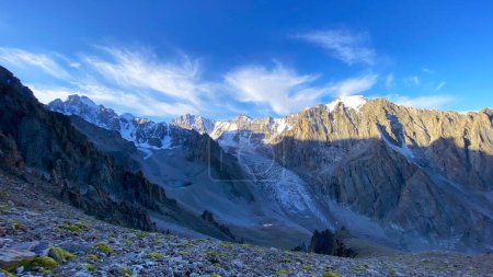 Foto de Amanecer en las montañas. La cresta kirguisa. Parque Nacional Ala Archa en Kirguistán. Vacaciones de verano activas. Hermoso paisaje de montaña. Picos, rocas y crestas cubiertas de nieve. - Imagen libre de derechos
