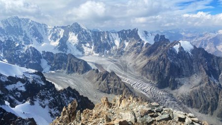 Foto de Vista del glaciar Ak-Say y la cresta kirguisa. Parque Nacional Ala Archa. Majestuosas montañas duras de Kirguistán. Hermoso paisaje de montaña. Picos cubiertos de nieve, rocas, colinas y laderas. Vacaciones activas de verano. - Imagen libre de derechos