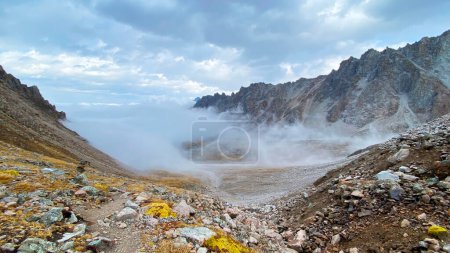 Foto de Increíblemente hermoso paisaje de otoño de montaña con nubes rastreras. Parque Nacional Ala-Archa, Kirguistán. Crestas, rocas, laderas y picos de la cresta kirguisa. Vacaciones activas en Asia. - Imagen libre de derechos