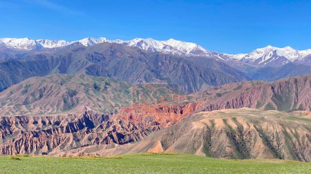 Top view of the Konorchek canyons in Kyrgyzstan. Colorful mountains. Amazing mountain landscape. The peaks of the mountains are covered with snow, and the sky is blue and clear.