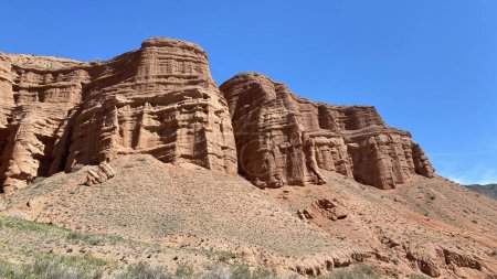 The famous Konorchek canyons in Kyrgyzstan. A rocky red mountain against a clear blue sky. A trip through the mountains of Kyrgyzstan. Weekend trekking.