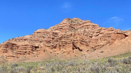 Large geological formations resulting from the weathering of rocks. Konorchek canyons in Kyrgyzstan. A red mountain against a blue sky. Trekking in the mountains of Kyrgyzstan