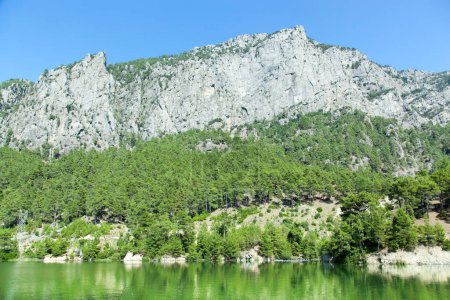 Der malerische Blick auf den grünen Karacaoren-See mit Spiegelungen und einem steilen Berg (Provinz Antalya, Türkei)).