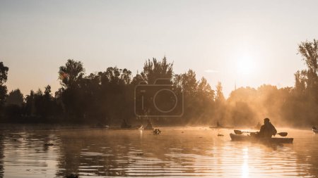 Sunrise and silhouettes of people paddling kayaks in Xochimilco, Mexico