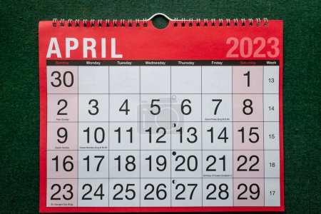 Photo for Calendar 2023, April, monthly planner. Day, month, year, date and activity organiser wall and desk planner. Red and white calendar with large letters and numbers on green background. - Royalty Free Image