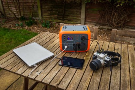 Photo for Portable power station solar electricity generator with laptop, tablet and camera electronic devices charging. Wireless charging lithium battery backup for power outage emergencies outdoors or camping - Royalty Free Image