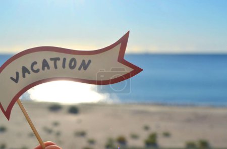 Photo for Stick with paper speech bubble with words Vacation on background sea, sky, sandy beach on a sunny summer day. Text-balloons with text from letters. Concept, symbol, sign vacation travel tourism rest. - Royalty Free Image
