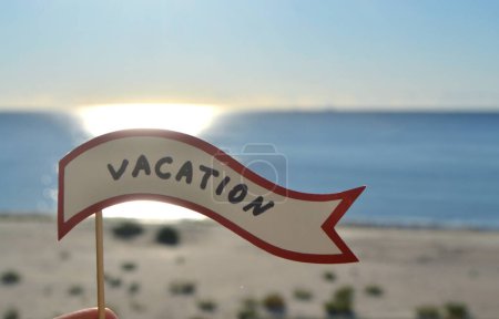 Photo for Stick with paper speech bubble with words Vacation on background sea, sky, sandy beach on a sunny summer day. Text-balloons with text from letters. Concept, symbol, sign vacation travel tourism rest. - Royalty Free Image