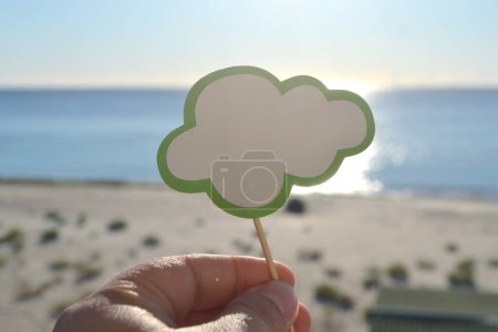 Photo for Stick with paper empty speech bubble on background blue sea, sky, sandy beach in hand on sunny summer day. Text-balloons with space for text. Concept, symbol, sign vacation travel tourism rest holiday - Royalty Free Image