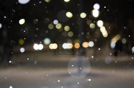 Photo for Blurred background. City view, lights, falling snow, night, street, bokeh spots of headlights of moving cars. Diffuse Urban backdrop winter scenery of street in city at night. Lantern light, snowfall - Royalty Free Image