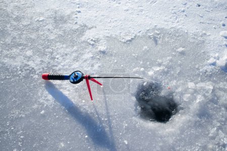 Photo for Winter ice fishing. Ice fishing in the winter. Small fishing rod stands near a hole in the ice of a river on a sunny day. Winter activity - Royalty Free Image