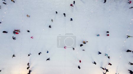 Foto de Muchas personas patinando en una hermosa pista de patinaje sobre hielo al aire libre decorado Año Nuevo Iluminaciones de Navidad, decoraciones, guirnaldas luminosas en la noche de invierno. Celebración de Navidad de Año Nuevo. Antena - Imagen libre de derechos