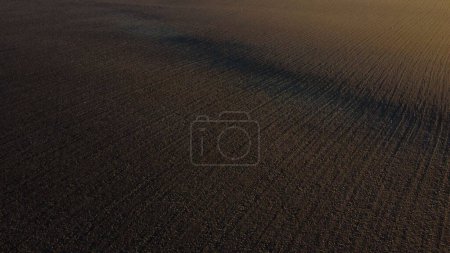 Photo for Landscape of plowed up land on an agricultural field on a sunny autumn day. Flying over the plowed earth with black soil. Agrarian background. Black soil. Ground earth dirt priming aerial drone view. - Royalty Free Image
