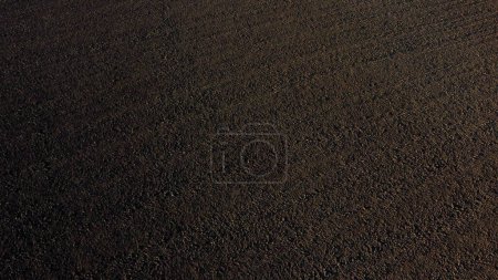 Photo for Landscape of plowed up land on an agricultural field on a sunny autumn day. Flying over the plowed earth with black soil. Black soil. Ground earth dirt priming aerial drone view. Agrarian background - Royalty Free Image