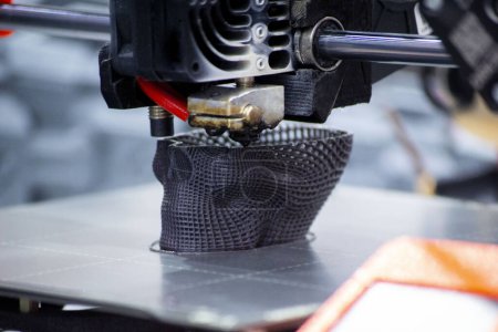 3D-Drucker-Prototyp eines menschlichen Schädels aus geschmolzenem Plastik. Prozess der Erstellung eines Prototyp-Modells des menschlichen Schädels mit 3D-Drucker aus geschmolzenem schwarzem Kunststoff in Nahaufnahme. Additive neue Druckertechnologie