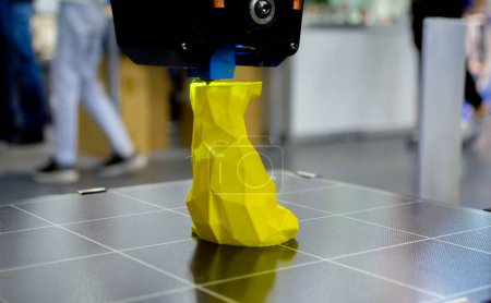 Foto de Prototipo de impresión de impresora 3D de juguete de plástico fundido. Proceso de creación de prototipo de modelo de juguete en la impresora 3D desde el primer plano de plástico fundido amarillo. Tecnología de impresora adicional nueva. Impresión moderna - Imagen libre de derechos