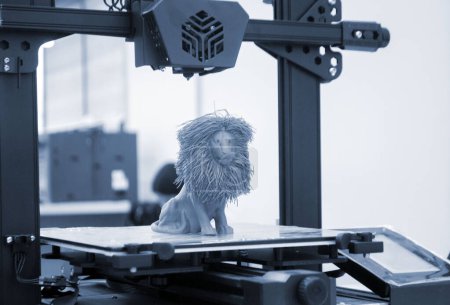 Foto de Modelo de león de juguete impreso en la impresora 3D de plástico fundido de color azul en el escritorio de la impresora 3D. Concepto Impresora 3D, impresión 3D, modelado de prototipos de objetos tridimensionales. Producción innovadora - Imagen libre de derechos