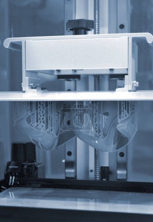 Foto de Modelos impresos en el primer plano de la impresora 3D. Objetos impresos en la impresora fotopolímero sla 3D a partir de resinas fotopolímeros líquidos en la plataforma de impresión dentro de la impresora 3D. Tecnología moderna de aditivos progresivos. - Imagen libre de derechos