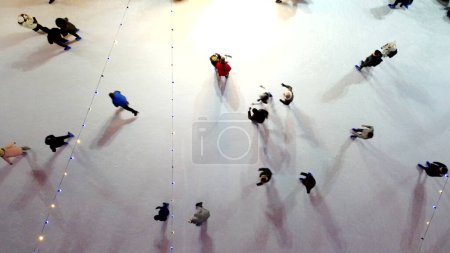 Foto de Muchas personas patinando en una hermosa pista de patinaje sobre hielo al aire libre decorado Año Nuevo Iluminaciones de Navidad, decoraciones, guirnaldas luminosas en la noche de invierno. Celebración de Navidad de Año Nuevo. Antena - Imagen libre de derechos