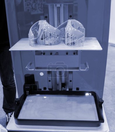 Printed models on 3D printer close-up. Objects printed on photopolymer sla 3D printer from liquid photopolymer resins on printing platform inside 3d printer. Modern progressive additive technology.