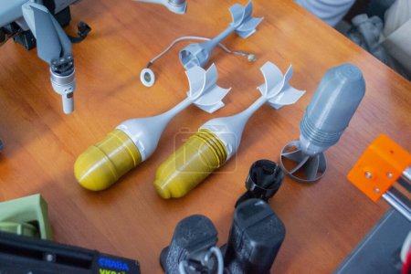 Prototype model of rocket bomb tip printed on 3D printer. Small colored models of tail fins, tail cone printed on 3D printer from molten plastic on table. New modern innovation printing technology