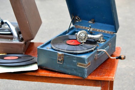 An old retro record playing on an old vintage gramophone at a flea market. The work of portable gramophone. Old vintage shabby record player, phonograph, potefone