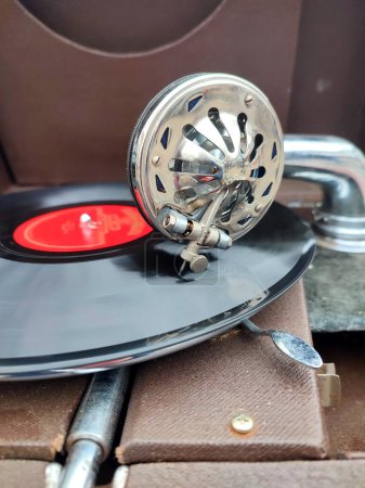 An old retro record playing on old vintage gramophone at flea market. Work of portable gramophone. Old vintage shabby record player, phonograph, potefone. Needle close up. Nostalgia antique turntable